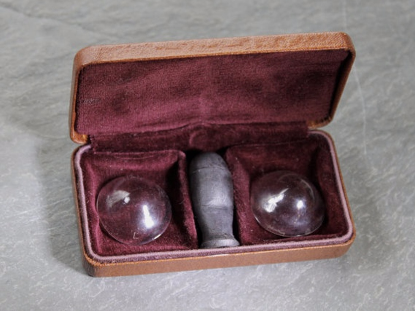 An image of semi-spherical solid glass contacts meant to cover the whole eye, resting in a felt-lined case